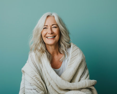 an older woman is wrapped in a blanket and smilingの素材