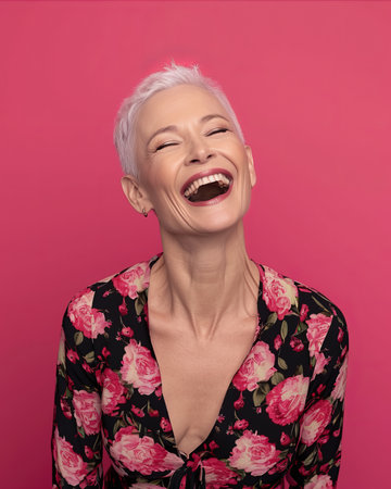 a woman with short white hair laughing on a pink backgroundの素材