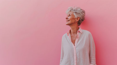an older woman standing in front of a pink wallの素材
