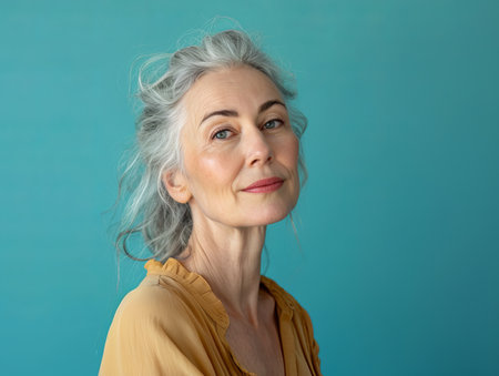 an older woman with gray hair posing against a blue backgroundの素材