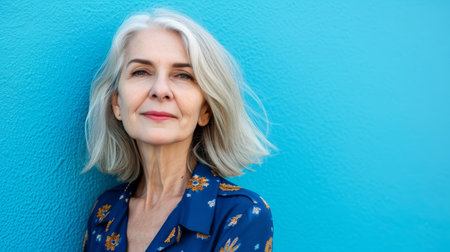 an older woman with gray hair standing against a blue wallの素材