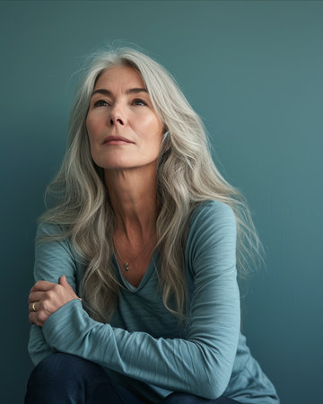 an older woman with gray hair sitting on a blue backgroundの素材