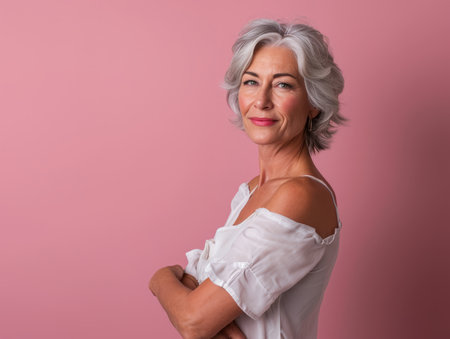 an older woman with gray hair standing in front of a pink backgroundの素材