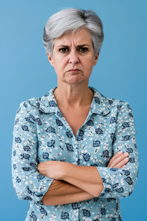 an older woman with her arms crossed against a blue backgroundの素材