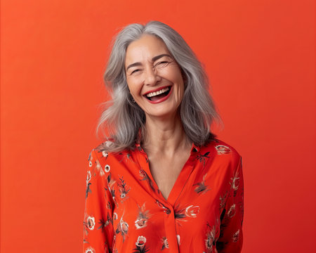 portrait of happy senior woman laughing isolated on orange background stock photoの素材
