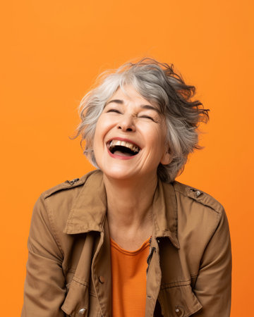 portrait of happy senior woman laughing on orange background stock photoの素材