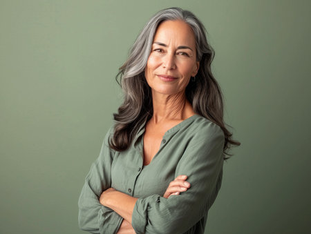 portrait of a mature woman with her arms crossed on a green backgroundの素材