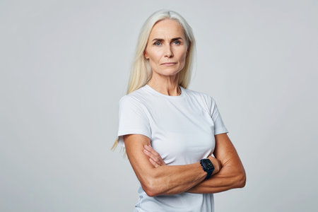 portrait of a mature woman standing with her arms crossed on a gray backgroundの素材
