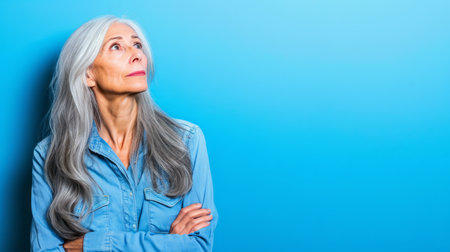 an older woman with gray hair standing against a blue wallの素材