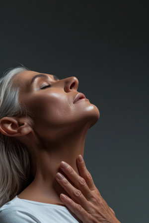 an older woman with her hands on her neckの素材