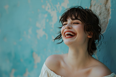 a woman is laughing in front of a blue wallの素材