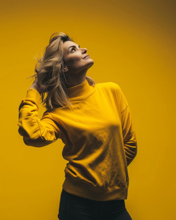 a woman in a yellow sweater standing on a yellow backgroundの素材