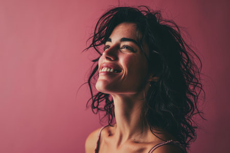a woman smiling with her eyes closed on a pink backgroundの素材