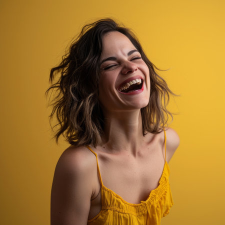 a woman is laughing and smiling in front of a yellow backgroundの素材