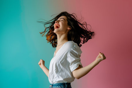 a woman in a white shirt and blue jeans is jumping up and down on a colorful backgroundの素材