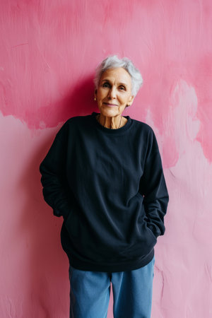 portrait of senior woman standing in front of pink wallの素材
