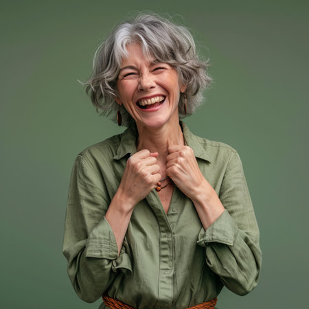 a woman with gray hair and a green shirt is laughingの素材