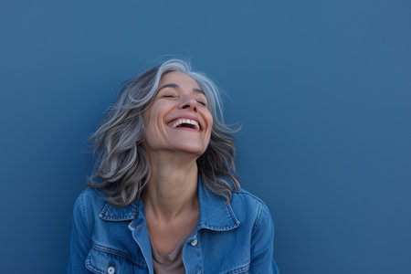 a woman with gray hair and a denim jacket is laughingの素材