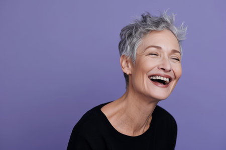 a woman with gray hair smiling and laughing on a purple backgroundの素材