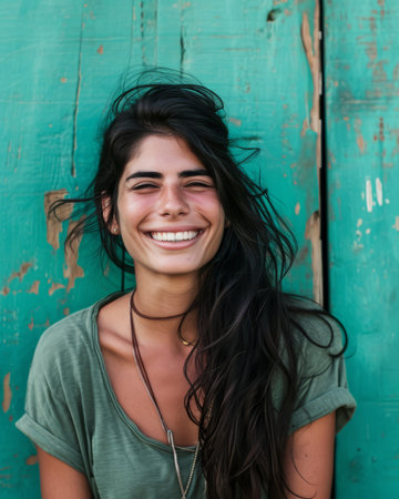 a woman with long hair smiling in front of a green wallの素材
