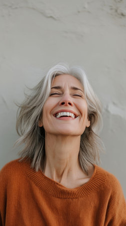smiling woman with gray hair and an orange sweaterの素材