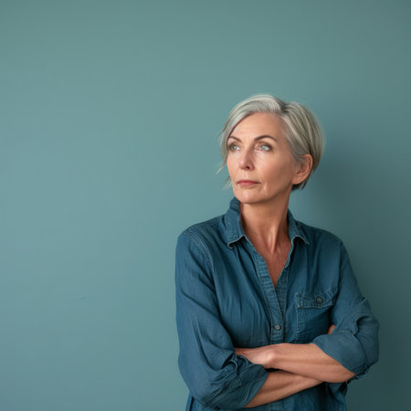 an older woman standing with her arms crossed against a blue wallの素材