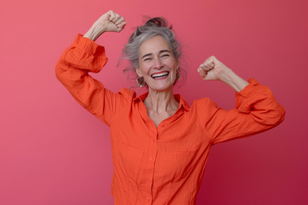 an older woman in an orange shirt is showing off her musclesの素材
