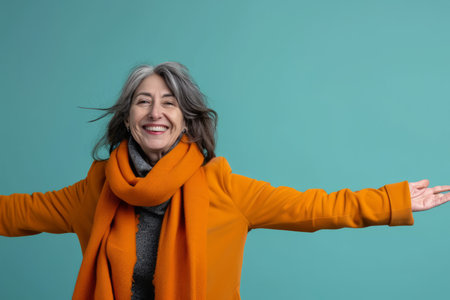 an older woman with her arms outstretched in an orange coatの素材