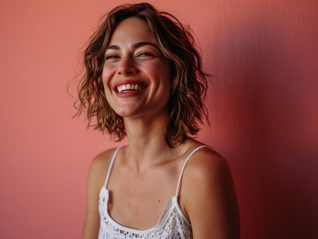 portrait of a smiling woman against a pink wallの素材