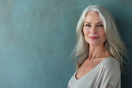 an older woman with gray hair posing against a blue wallの素材