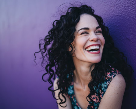 smiling woman with curly hair against purple wallの素材