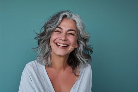 smiling woman with gray hair and white shirt on blue backgroundの素材