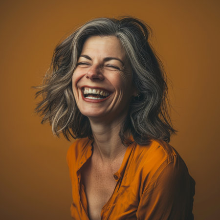 portrait of a happy woman laughing on an orange backgroundの素材