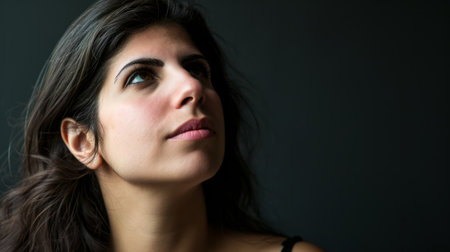 portrait of a young woman looking up on a black backgroundの素材