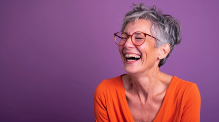 an older woman with glasses and an orange shirt laughingの素材
