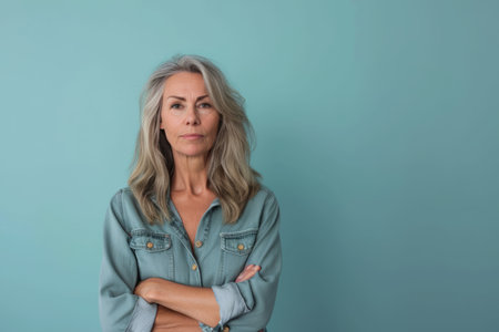 an older woman standing with her arms crossed against a blue backgroundの素材