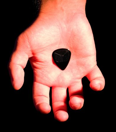 hand with guitar plectrum on palm isolated on blackの写真素材