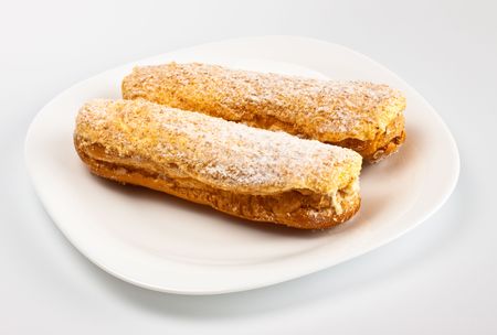 two eclairs on white dish grey background