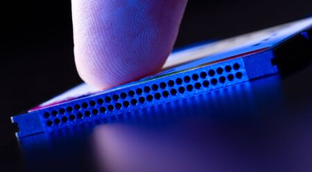 finger on flash card in blue light closeup, dark backgroundの写真素材