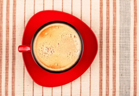 red coffee cup on striped tablecloth top viewの写真素材