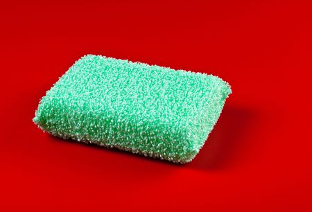green plastic sponge on red backgroundの写真素材