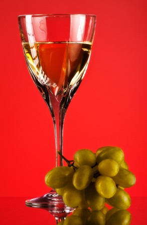 glass of white wine and grape, red backgroundの写真素材