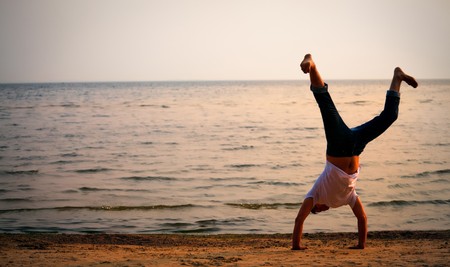 man doing handstand on sunset beachの写真素材