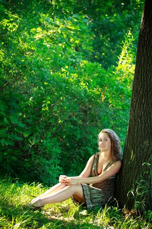beautyful woman sitting next big treeの写真素材