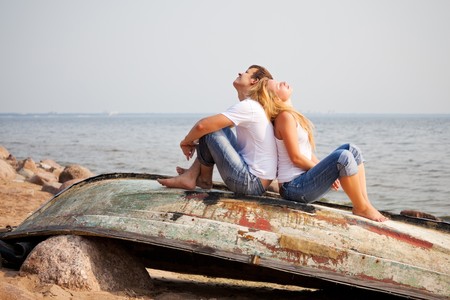 couple sitting on old boat back to back couple sitting on old boat back to back