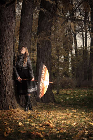 girl with umbrella in autumn park at eveningの写真素材