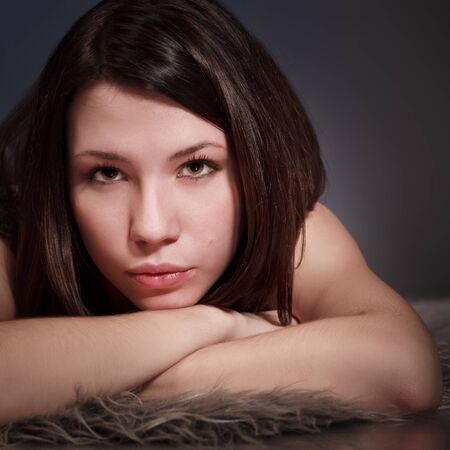 beautiful brunette girl portrait, serious, laying on furの写真素材