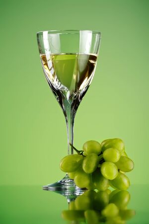 glass of wine and grape bunch, green backgroundの写真素材