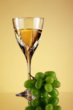 glass of wine and grape bunch, beige backgroundの写真素材