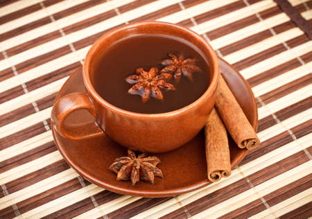 cup of winter tea with cinnamon and star anise on bamboo napkinの写真素材